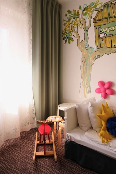 Rocking horse, three stools and a pink, flower-shaped lamp on the wall. 