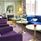 En blå soffa och flera lila fåtöljer och runda pelarbord i lobbyn. 