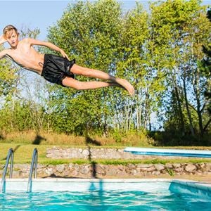 Boy jumping into the outdoor pool. 
