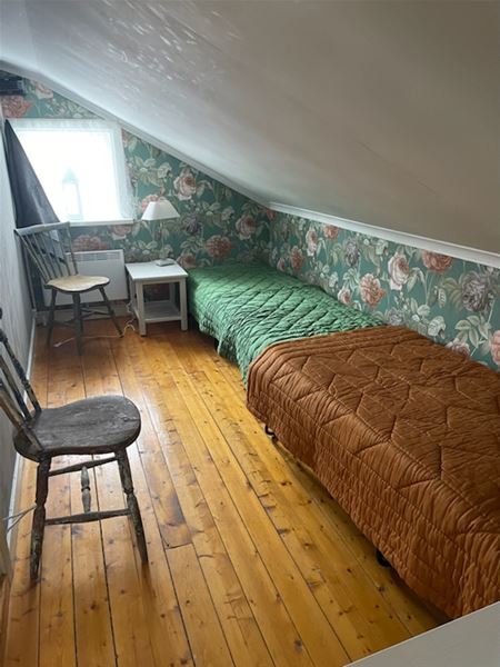 Sovrum med två enkelsängar på rad under snedtak. 