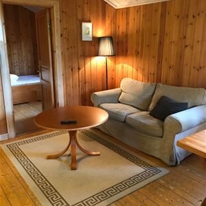 Beige soffa med runt bord i ett rum med väggar, golv och tak av furu.