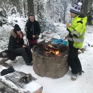 Three persons having a barbecue in the winter. 