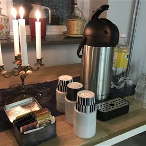 Lighted candles and a coffee thermos on a table. 