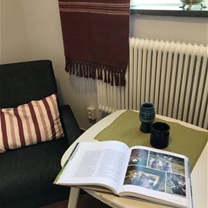Magazine on a small table with an armchair beside. 