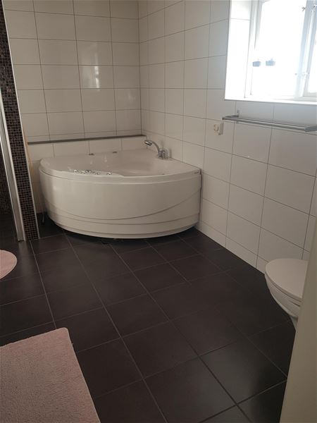 Tiled bathroom with a bath rub in the corner. 
