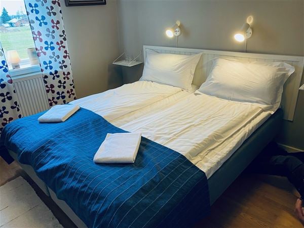 Double bed with dark blue bed cover.  