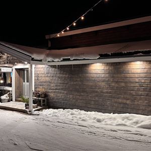 Exterior of a timber house, lighted up in the winter darkness. 