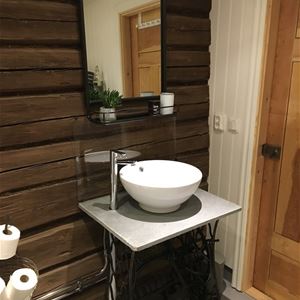 Washbasin on a sewing machine stand in front of a timber wall. 