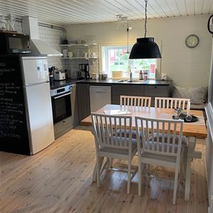 Kitchen with dark cupboards and dining furniture for four persons. 