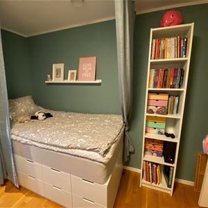 Bedroom with a single bed place on cupboards behind curtains. 