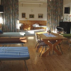 Dormitory with beds and a table with chairs in the middle. 