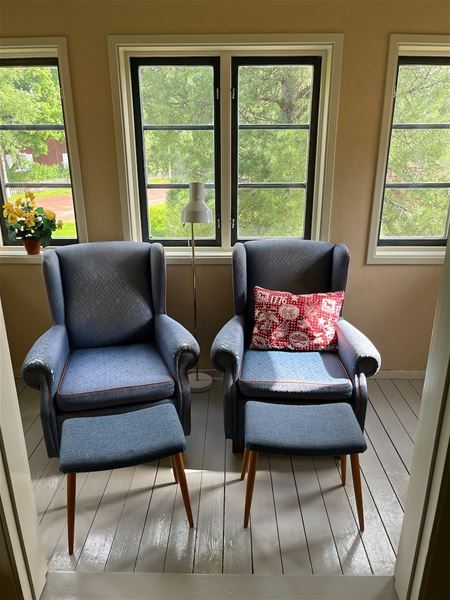 Two armchairs in front of large windows.  