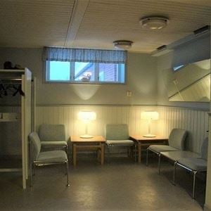 Room in the basement with chairs and small tables along the walls. 