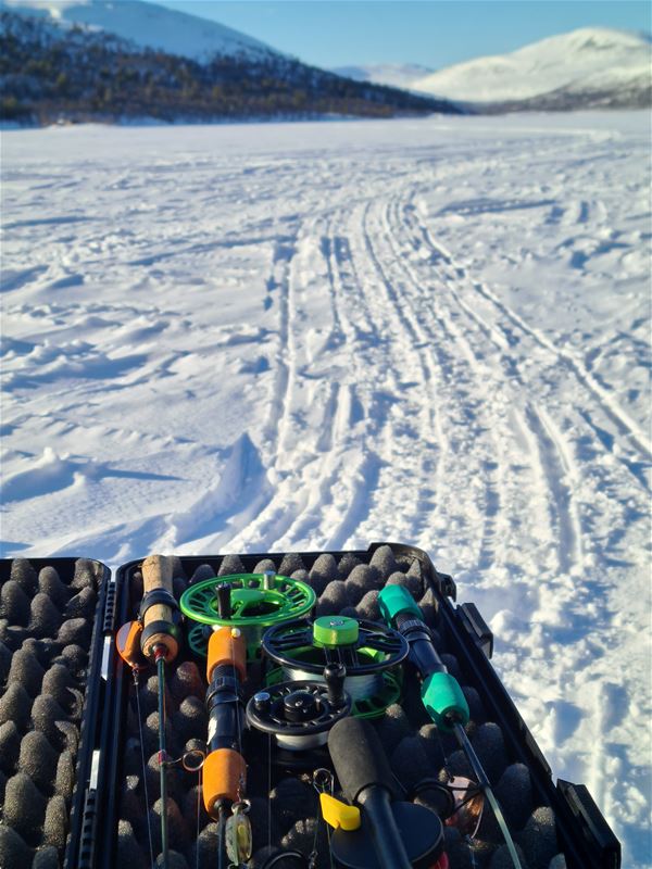 Fiskelåda med fiskespön på isen. 