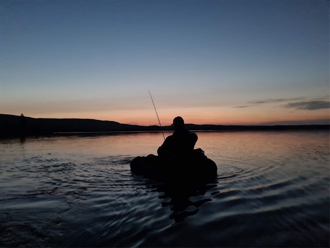 Fiskare i båt i solnedgången. 