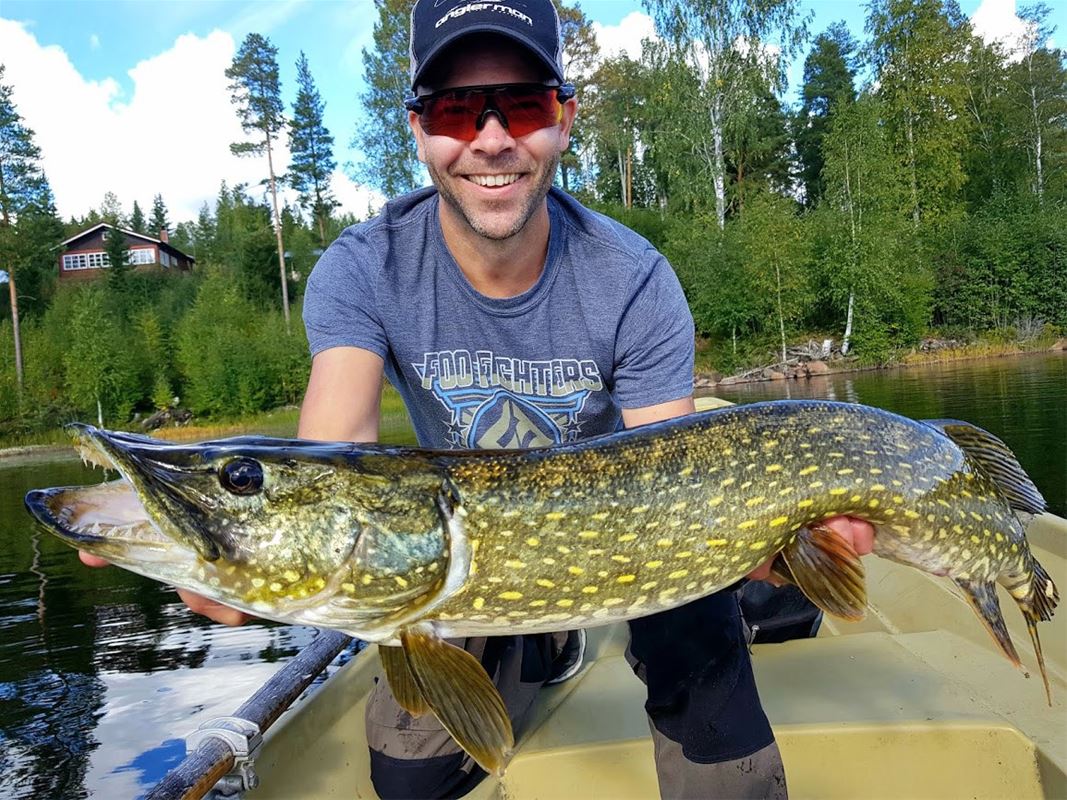 Fisherman holding up a large pike. 