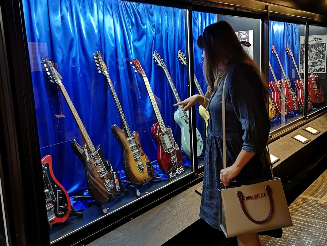 Kvinna står framför en monter med gitarrer.