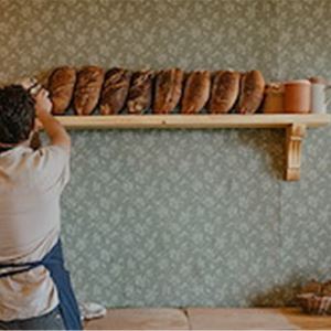 Person som lägger upp bröd på en hylla.