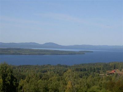 Utsikt över sjön Siljan och blå berg och grönskande träd. 