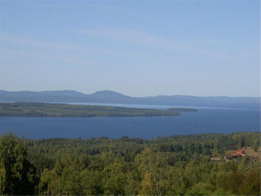 Utsikt över sjön Siljan och blå berg och grönskande träd. 