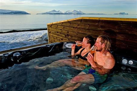 Two guests enjoying a drink in a jacuzzi outside