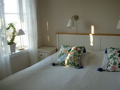 Double bed with white bedspread and floral pillows. 