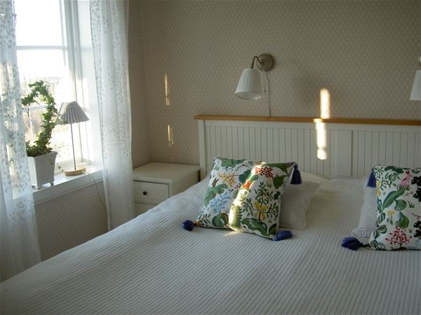 Double bed with white bedspread and floral pillows.  