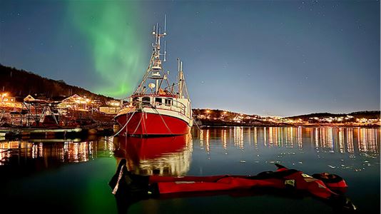 A guest floating in the water under the northern lights