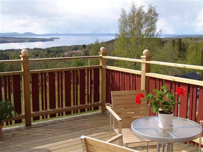 Balcony with red-painted railing and a view over lake Siljan. 