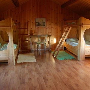 Two massive bunkbeds in a large room with pine walls and roof.