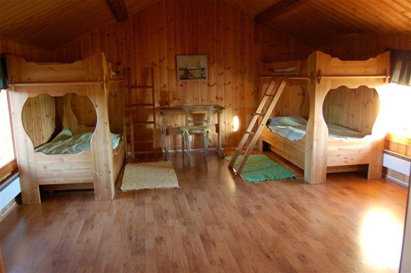 Two massive bunkbeds in a large room with pine walls and roof. 