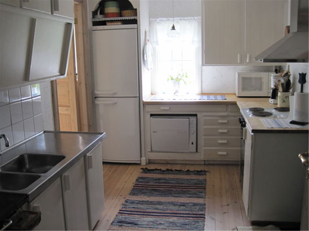 Fullutrustat kök med diskbänk, kyl o frys och  fönster vid köksbänken.