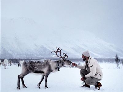Person mater rein i snødekt landskap med fjell i bakgrunnen.