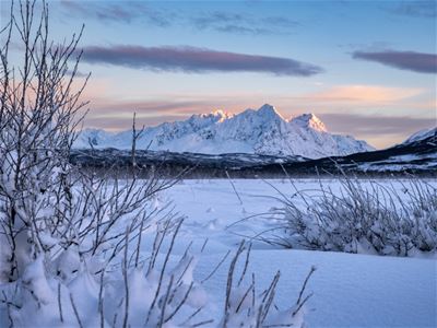 Snødekt landskap med fjell og fargerik himmel.