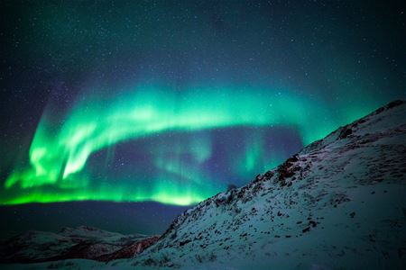 Bilde av nordlyset bak et snødekt fjell