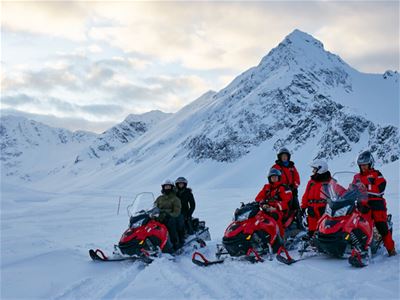 A group of people drving snowmobiles