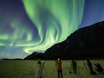Gjester ser på nordlyset som viser seg bak et stort fjell