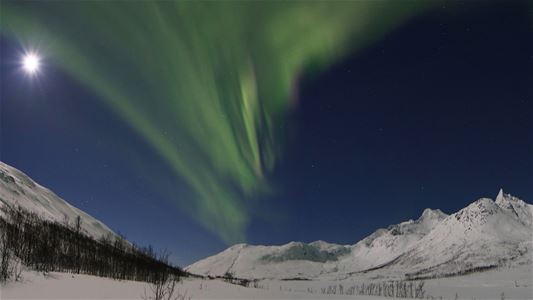 Snødekt fjellandskap og nordlys