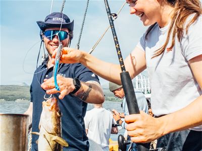 Guide hjelper gjest med fanget fisk