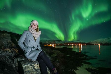 A guest sitting with the northern ligths in the background