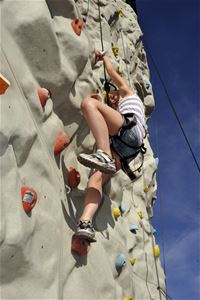 A kid upwards a climbing wall