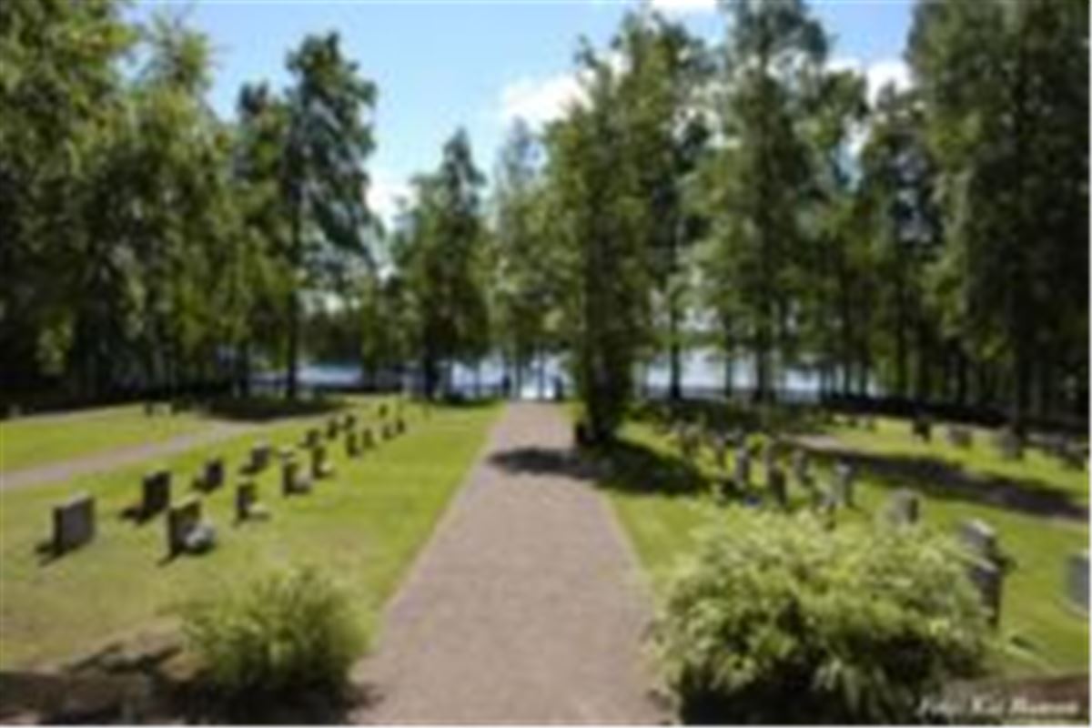 A small grave yard with trees and a lake