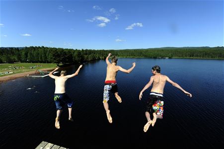 Tre pojkar som hoppar i badet