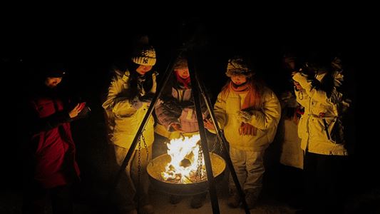 A group of guests sitting around a bonfire