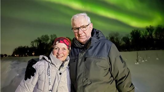 Two guests holding each other under the Northern Lights