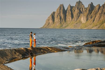 Two people looking at mejestic mountains from the shore