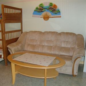 En soffa med soffbord i fotändan av en våningssäng.