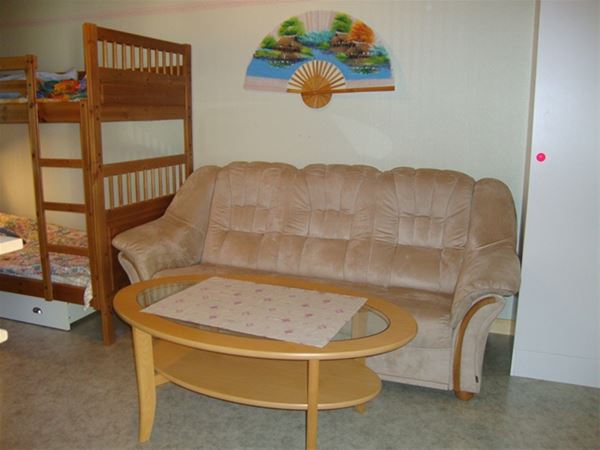 En soffa med soffbord i fotändan av en våningssäng. 