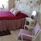 Dubbelsäng med rosa överkast och sängkappa i ett rum med blommiga tapeter. 