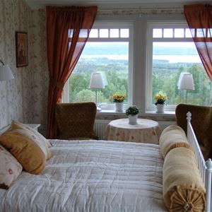 Double room with floral wall paper and red curtains. 